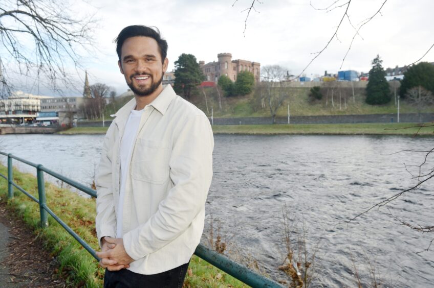 Gareth Gates wearing a white shirt and black hair and beard on the banks of the River Ness.