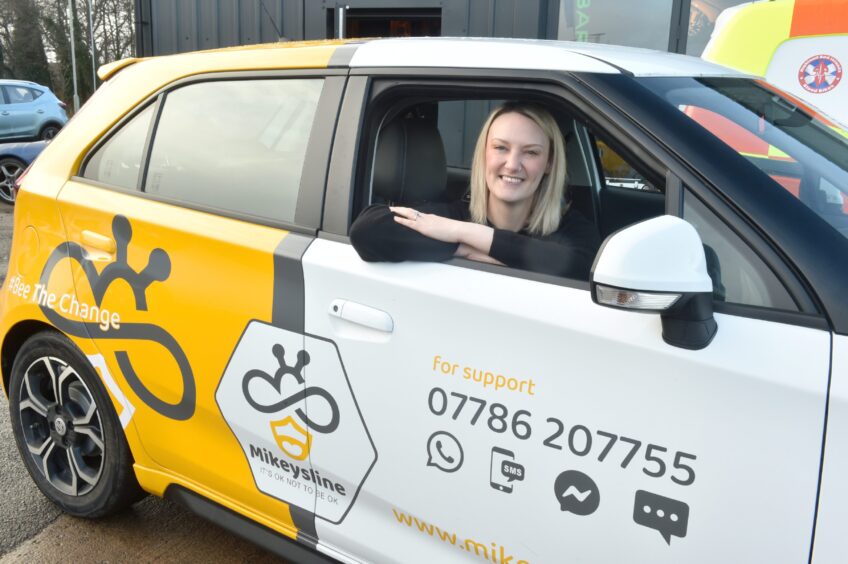 Jodie McCluskey of Mikeysline leans out of the driver's window of the charity's new yellow and white car.