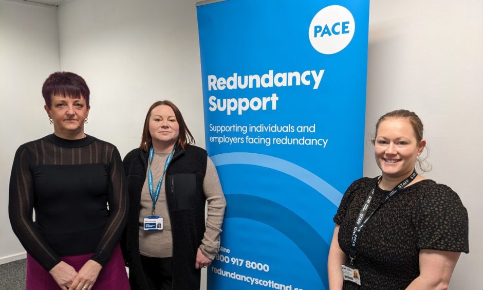 Teams standing in St Giles Centre unit next to "redundancy support" sign. 