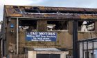 The aftermath of fire at Stag Motors. There is significant damage to the roof and the burnt-out interior can be seen from the gaping windows.