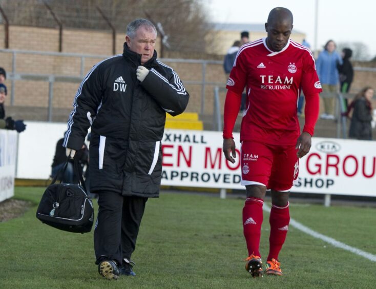 A Dons physio walks Aberdeen's Isaac Osbourne down the sideline as he is forced off with a hamstring injury against Forfar Athletic in January in January 2012. 