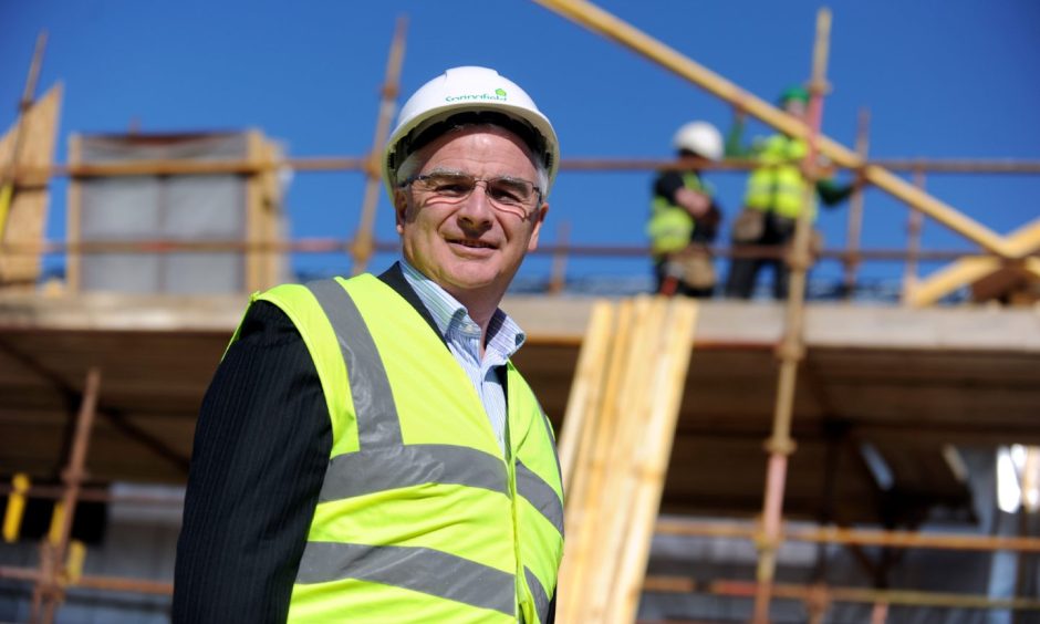 Sandy Adam in high-viz jacket and hard hat on construction site. 