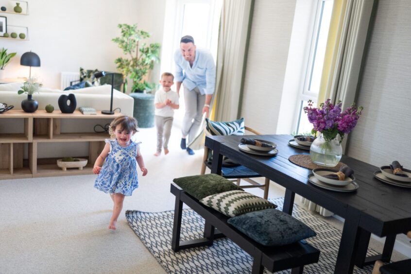 a dad playfully chasing two children in their new home