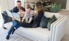 family with two small children reading on the sofa