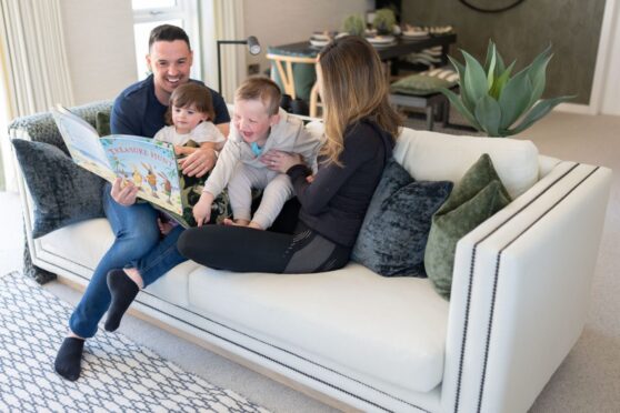 family with two small children reading on the sofa