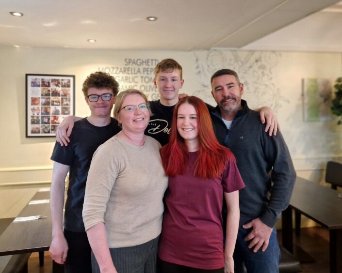 The family team at Scribbles Elgin stand in the Moray cafe smiling at the camera. 