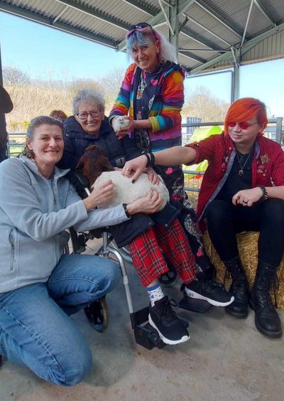 Sheila on an outing with her family. Sheila is pictured cuddling a lamb.