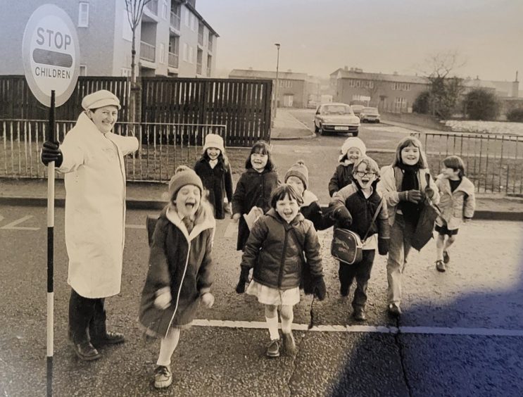 Sheila on her crossing in Northfield, with a group of happy children crossing the road under her watchful eye.