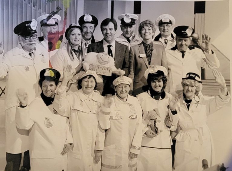 Sheila is pictured with lollipop ladies and lollipop men from around the country, alongside television presenter Russell Harty. A number carry soft toy good luck charms.