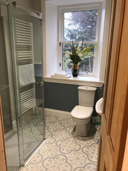 Modern bathroom with walk in shower and brown wooden doors.