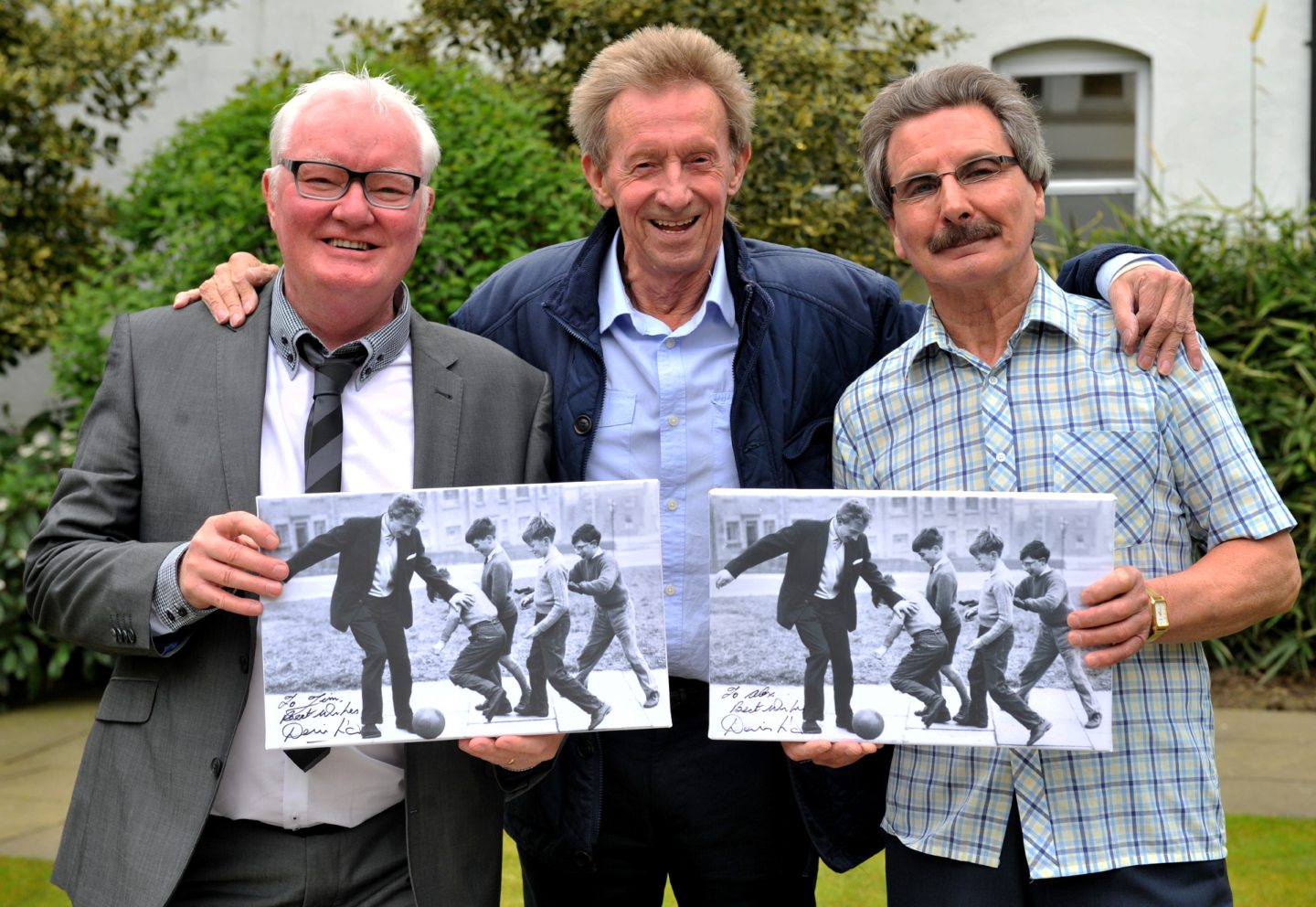 Denis Law presents a canvas print of the iconic EE picture of him having a kick-about with youngsters at Printfield to Alex Irvine and Jim Gray. Pictured is Denis Law with Jim Gray(left) and Alex Irvine(right) Picture by Richard Frew.