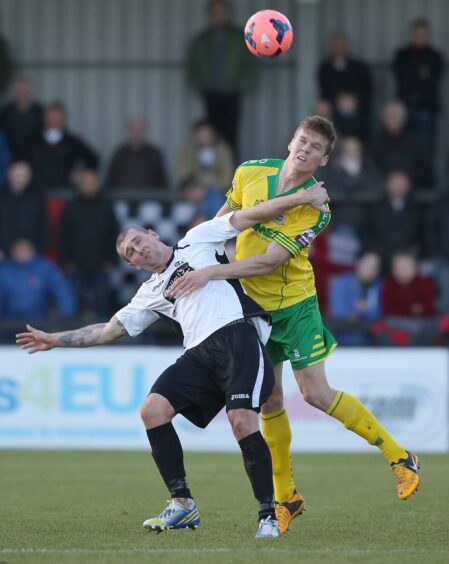 Tommy Wright in action for Corby Town, contesting a high ball against Dover Athletic in an FA Cup first round tie in 2013