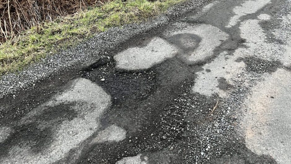 A patchy road, where little of the surface remains and there are sections of mud and loose stones.