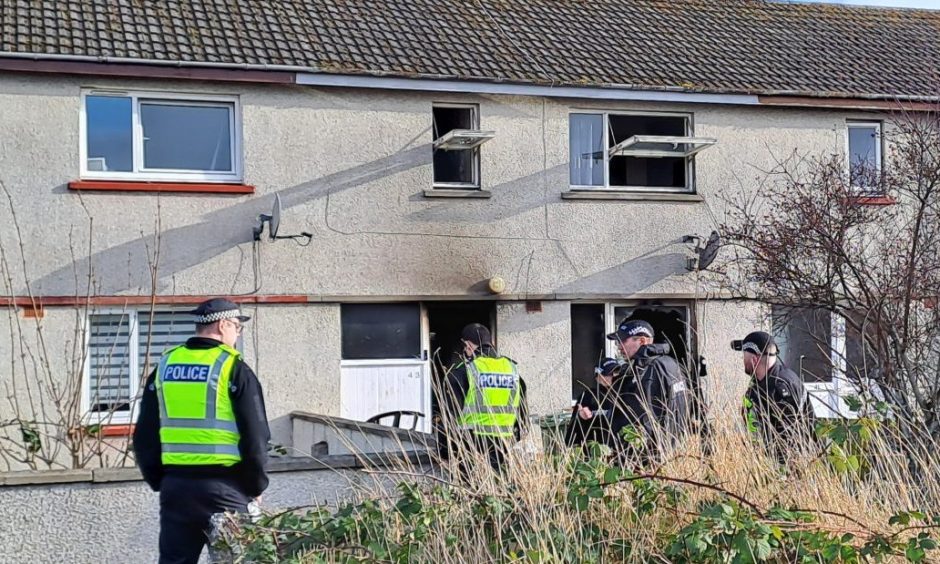 Several police officers outside the destroyed property