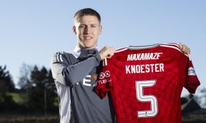 New Aberdeen signing Mats Knoester holds up a red club shirt with the number fife at Cormack Park. Image: SNS