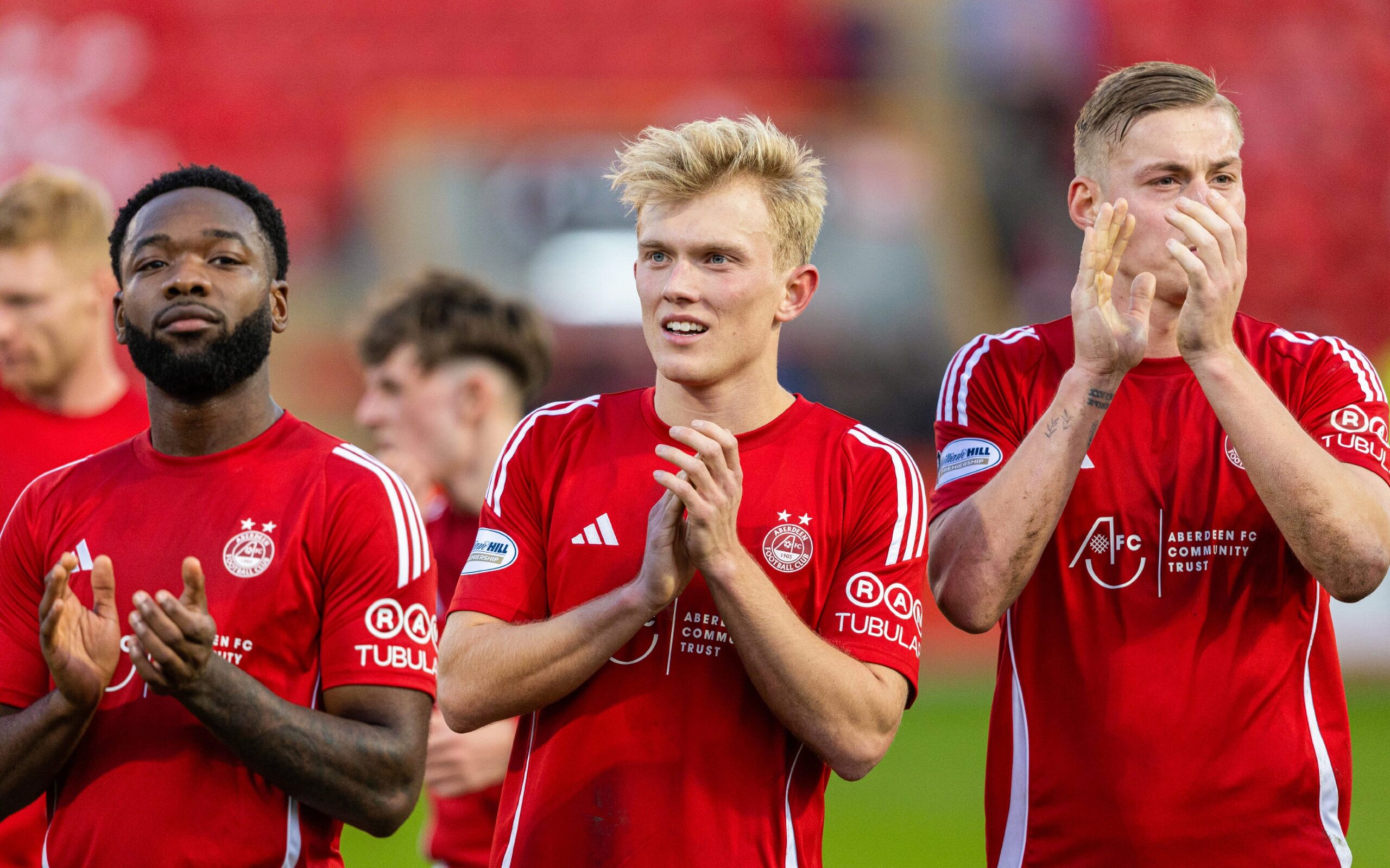 (L-R) Aberdeens Shayden Morris, Alexander Jensen and Kristers Tobers applaud fans at full after the 1-0 win against Kilmarnock at Pittodrie. Image: SNS 