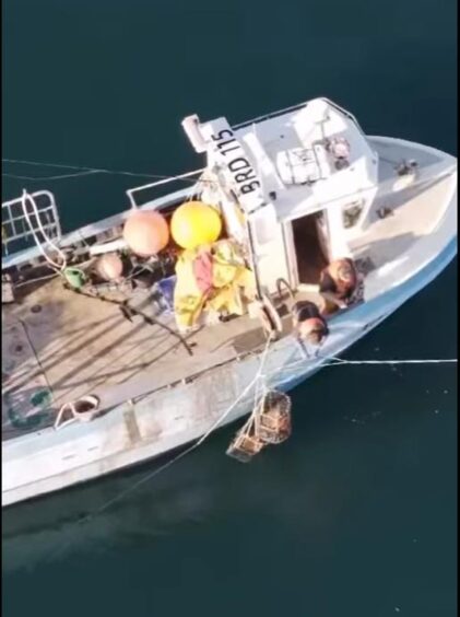 Highland creel fishermen Bally Philip and Haydn Mackenzie hanging over the edge of their vessel.