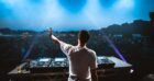 A DJ reaches an arm out over his decks at a music festival