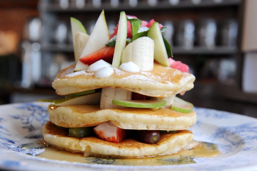 A stack of three pancakes with banana and other fruit at The Craftsman restaurant in Aberdeen