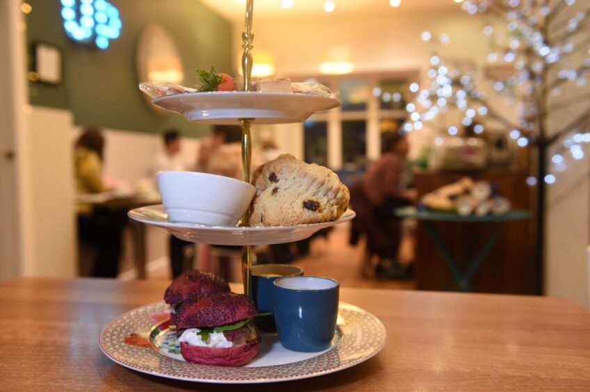 Three tiers of plates sit on a table at Cup. The plates are filled with scones and sandwiches.