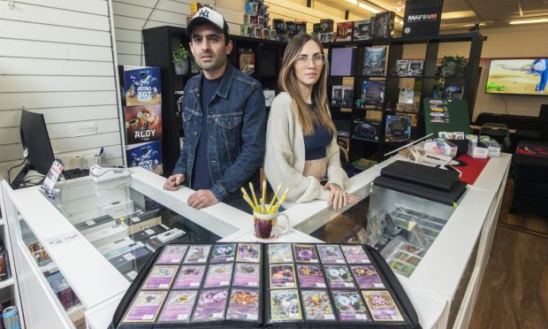 Staff behind counter in Game XP with trading cards on counter.