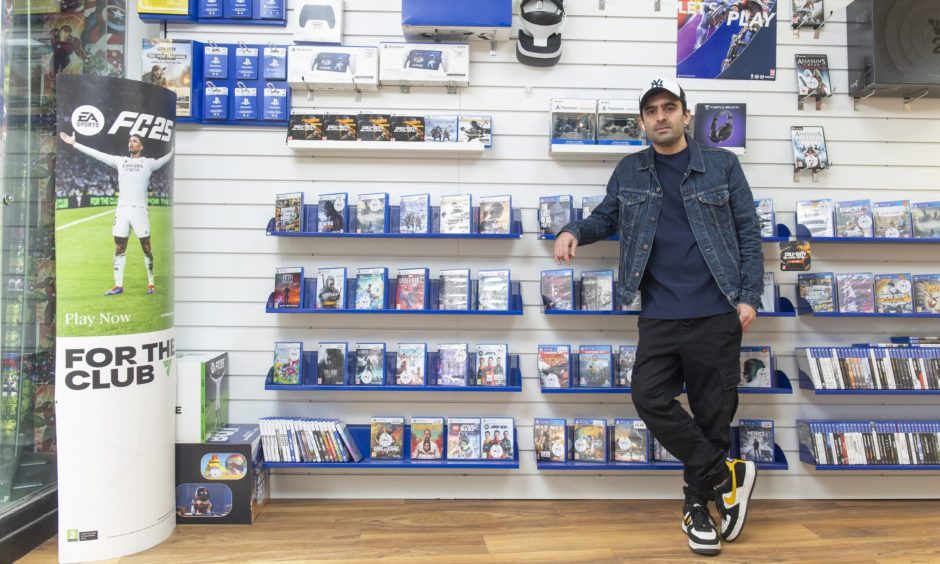 Amir Niazi leaning on shelves with games console games. 