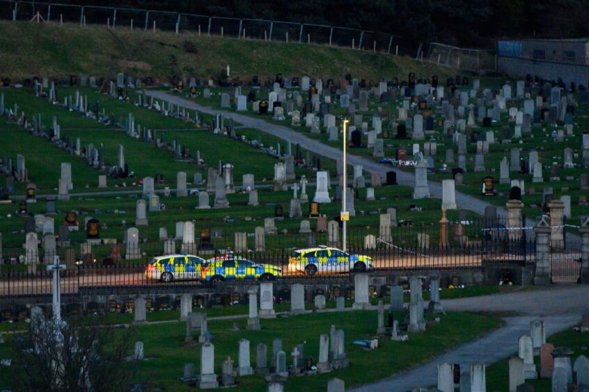 Police cars parked between Trinity Cemetery entrances.