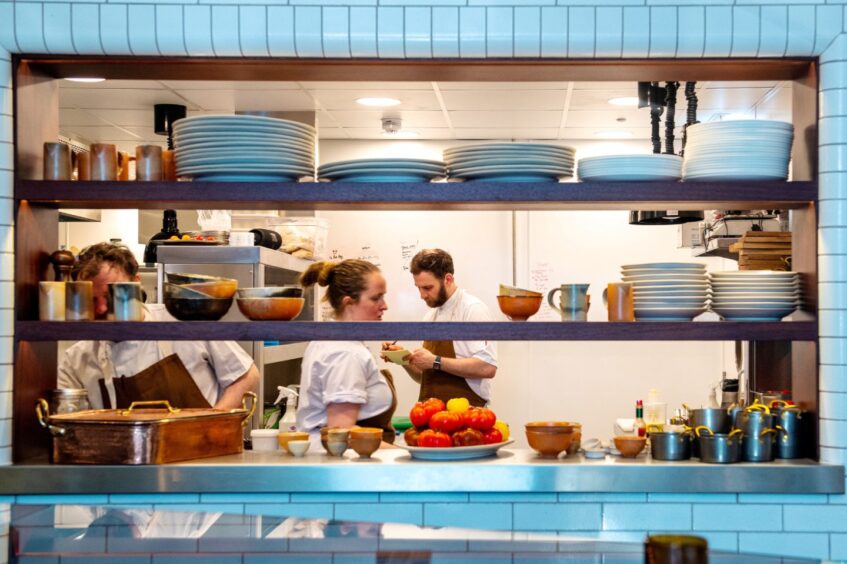 Chef's spotted through the gaps of metal shelving unit in the restaurant kitchen.