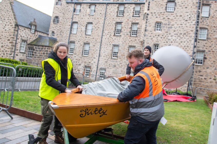 People wearing high-vis vests moving boat outside Marsichal Square 