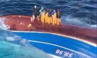 The crew of the Njord fishing trawler stranded on the hull of the vessel.