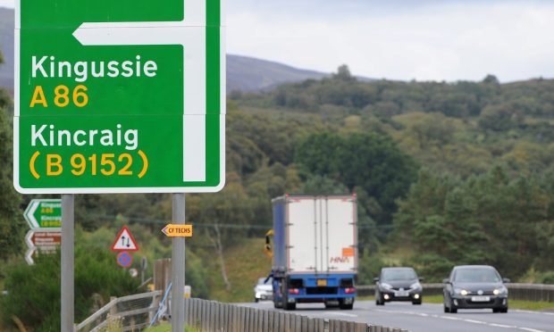 Traffic travelling on the A9 near Kingussie with turnoff to the village ahead.