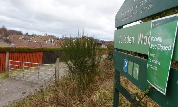 Green sign for Culloden Woods with gate across footpath on the left.