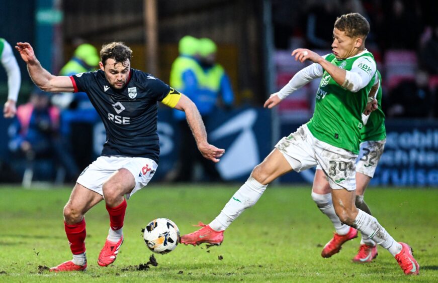 Ross County captain Connor Randall challenges for the ball with Hibernian forward Dwight Gayle.