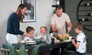 a family at a dinner table, parents serving three small boys