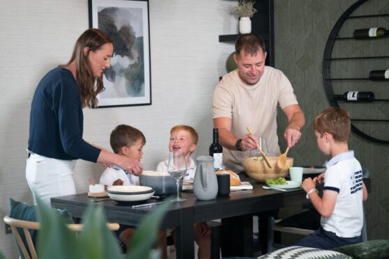 a family at a dinner table, parents serving three small boys