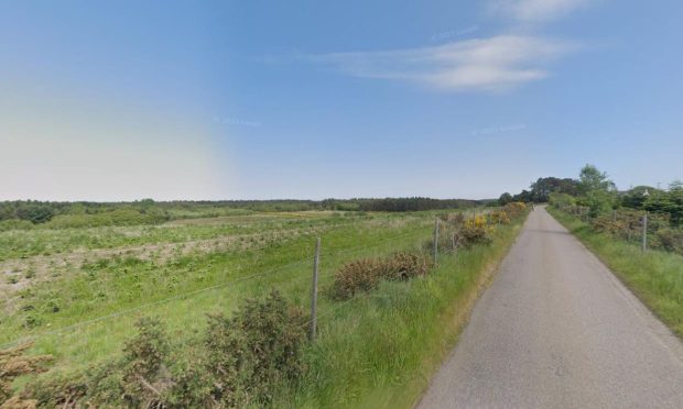 Agricultural land to the left of a single carriageway road.