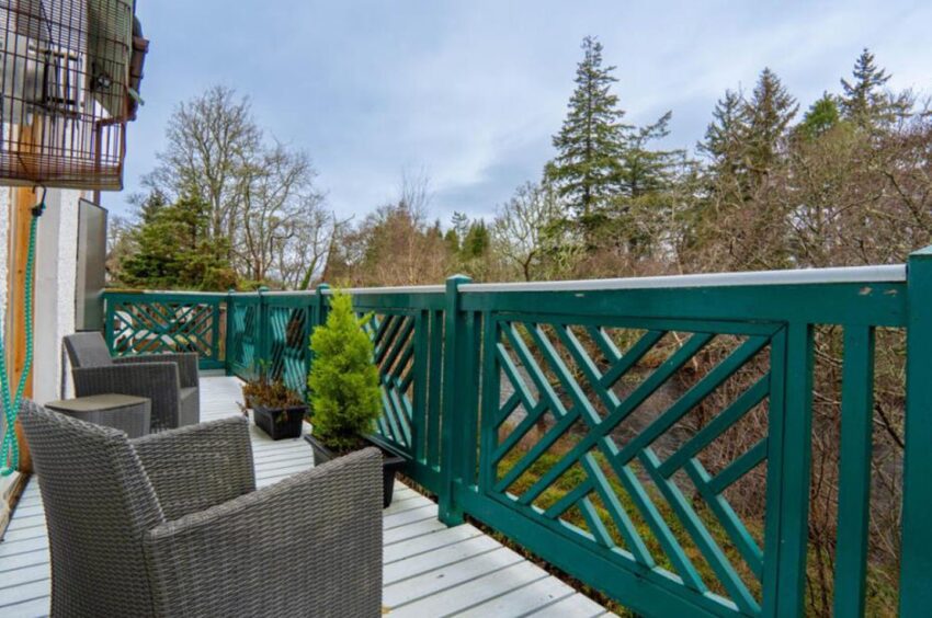 Turquoise balcony along the back of a qhite house.