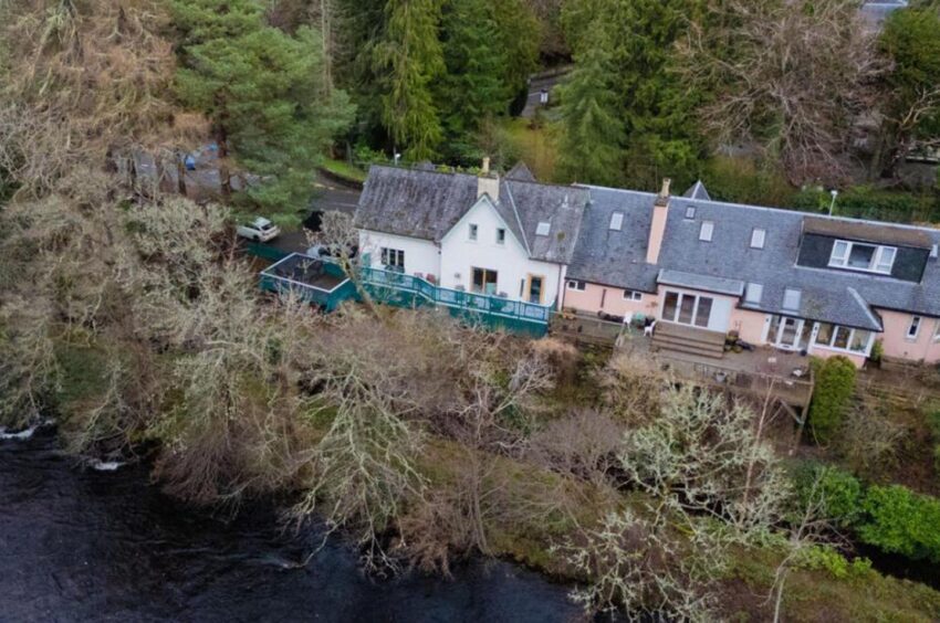 Aerial view of riverside home with balcony.