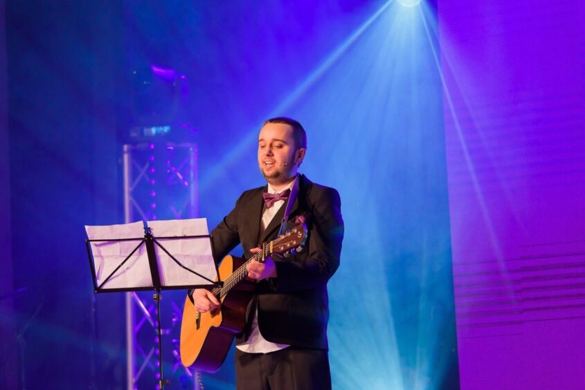 Older boy playing guitar on stage