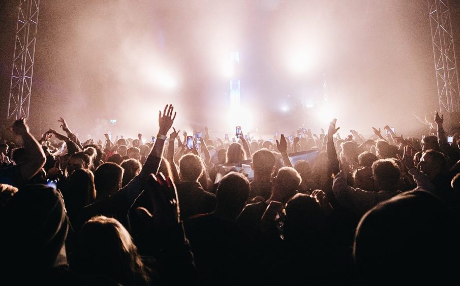 massive lights shine out over a crowd at a dance music festival