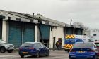 Picture shows cars parked outside industrial building damaged by fire.