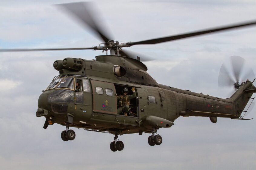 A crew member is visible within an airborne RAF Puma helicopter.