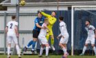 Rothes goalkeeper Sean McCarthy punches the ball away in a packed penalty box against Strathspey Thistle. Image: Jaserimage.