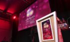 lit stage with a podium and a large screen carrying the branding of cHeRries Conference, which this year will tackle how to manage change at work