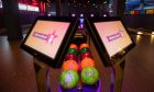 Bowling balls in two rows below two interactive screens