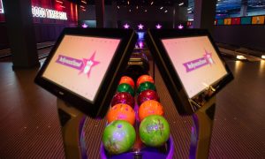 Bowling balls in two rows below two interactive screens