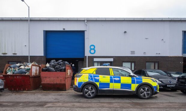 Police car and skips outside industrial unit in Portlethen