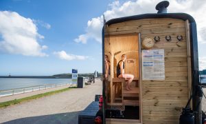 A woman looks out from inside a coastal sauna in Aberdeen