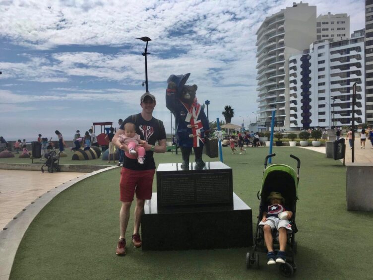 Baby Tamaya with her dad and brother next to a Paddington Bear statue 