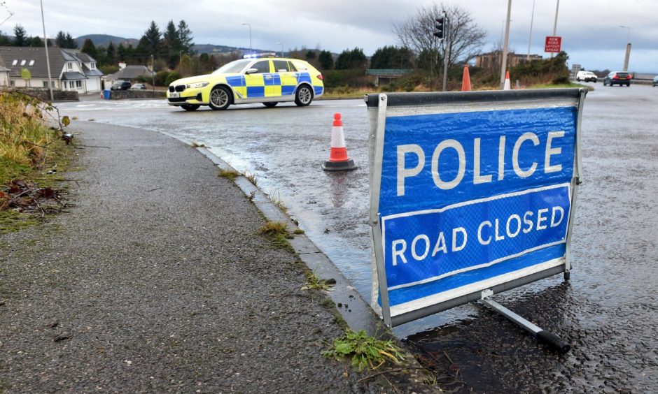 Police car with cones and a road closed sign.